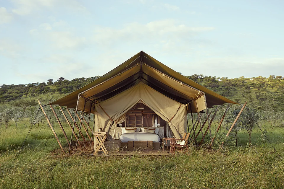 Luxury safari tent overlooking the Serengeti grasslands with an open-front bedroom and private veranda