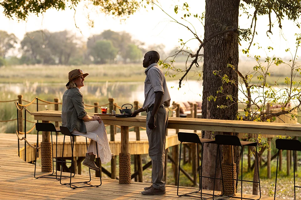 Guest enjoying outdoor dining overlooking the Okavango Delta at a luxury safari lodge in Botswana
