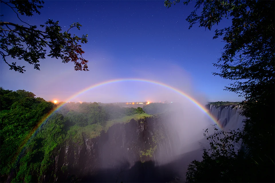 Moonbow arching over Victoria Falls beneath a clear, star-filled night sky