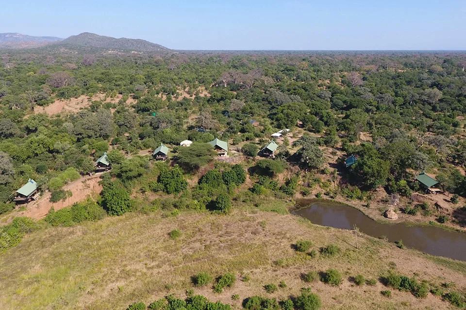 Aerial view of Kavinga Safari Camp surrounded by woodland and a seasonal waterhole