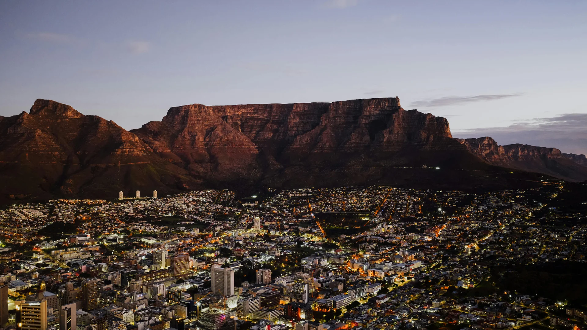 Cape Town city lights beneath Table Mountain at dusk, South Africa