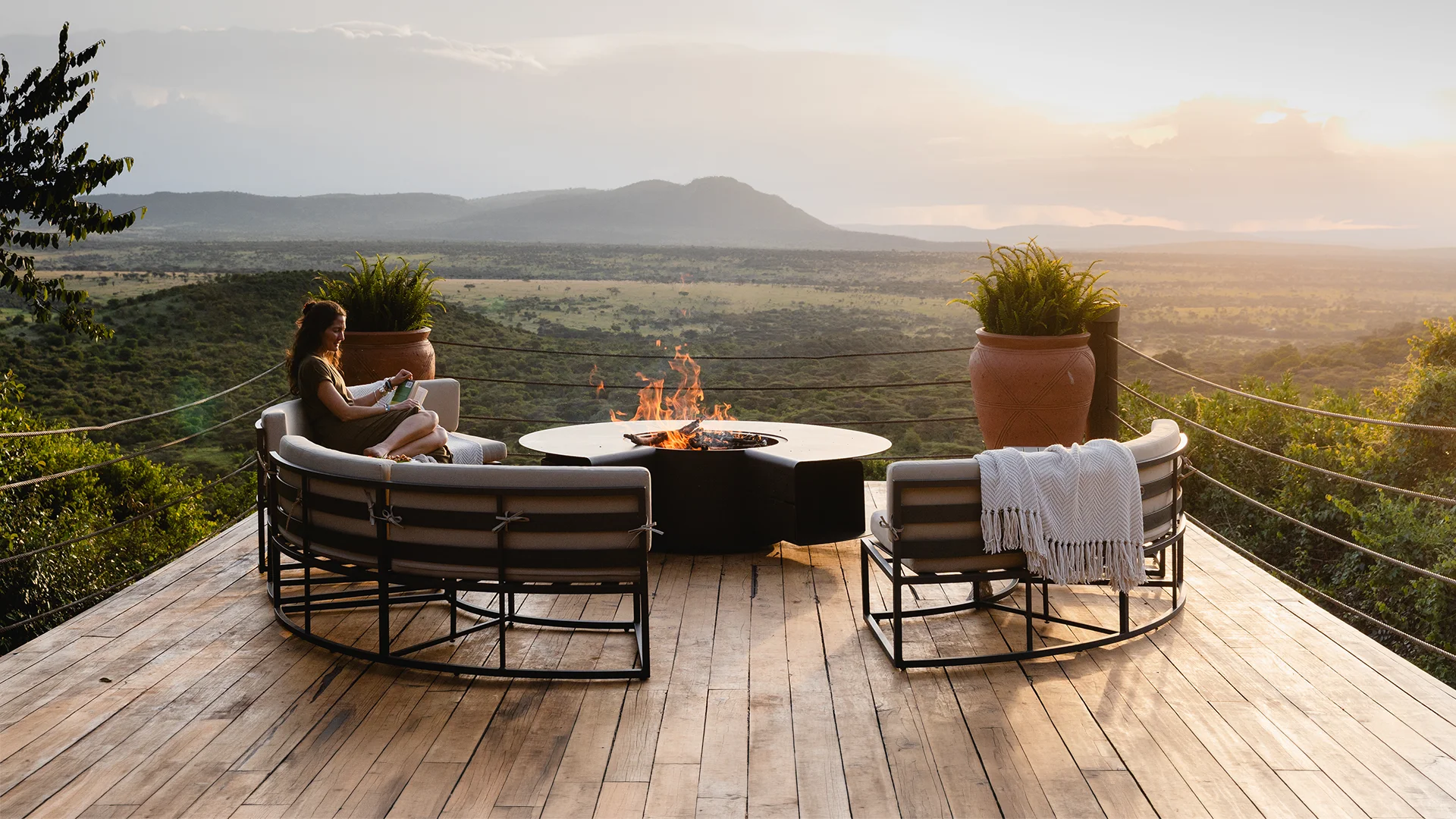 Guest relaxing on the outdoor deck at Cottar's Bush Villa overlooking the African savannah at sunset