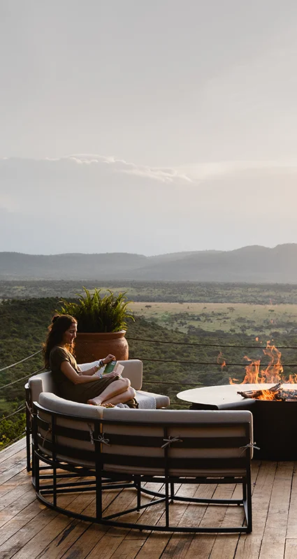 Guest relaxing on the outdoor deck at Cottar's Bush Villa overlooking the African savannah at sunset