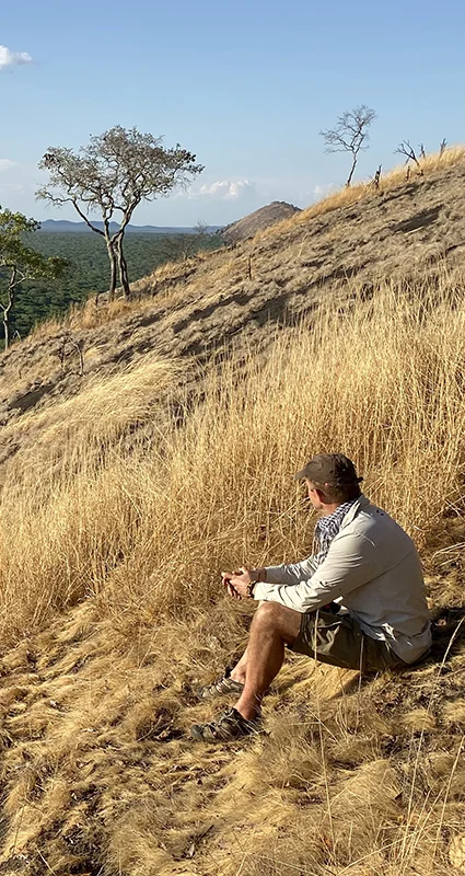 Guest resting on a rocky hillside overlooking the remote wilderness of Matobo National Park, Zimbabwe