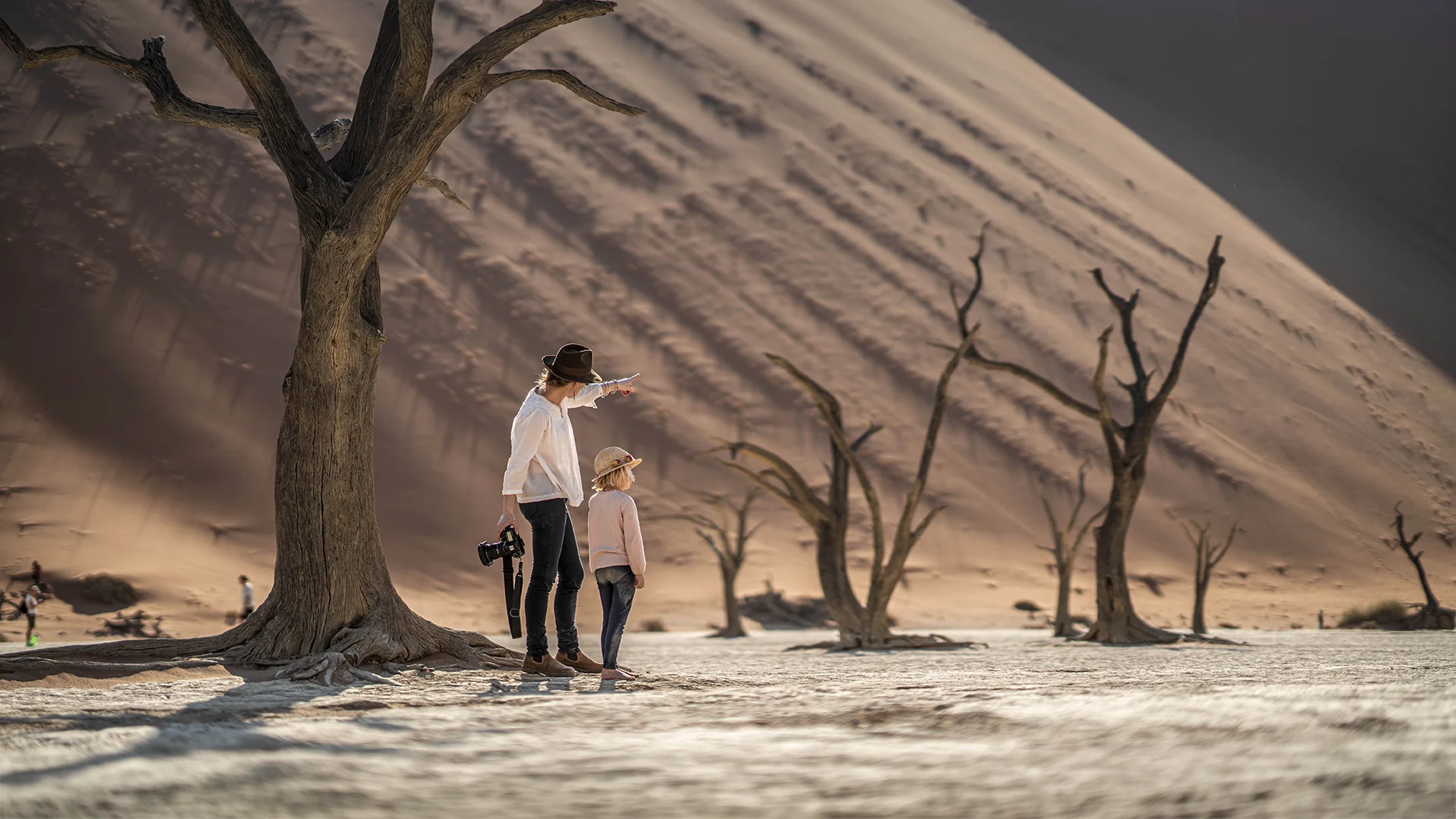Adult and child exploring the dead trees and towering dunes of Deadvlei, Namibia