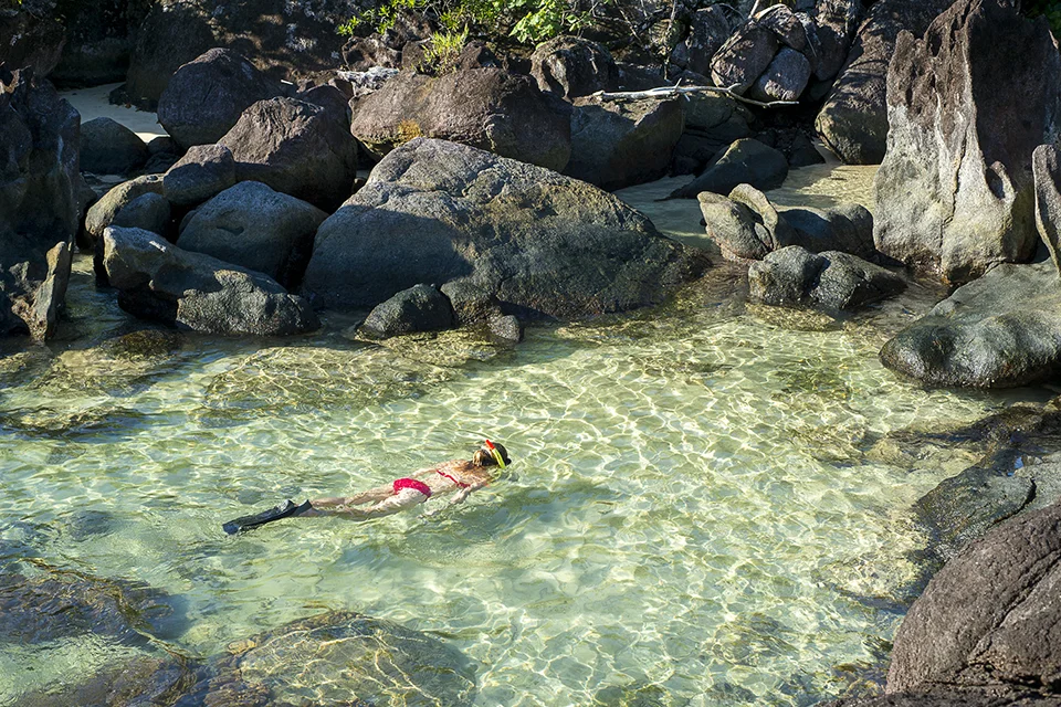 Guest snorkelling in a crystal-clear rock pool along a tropical African coastline