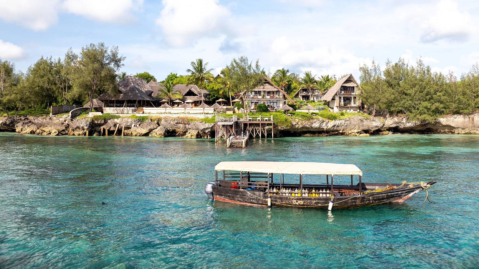 Sunshine Marine Lodge overlooking turquoise waters off Zanzibar, Tanzania, with a traditional dhow in the foreground