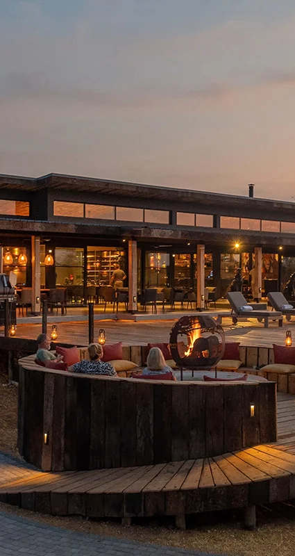 Guests relaxing around a fire pit at Ximuwu Lodge at sunset